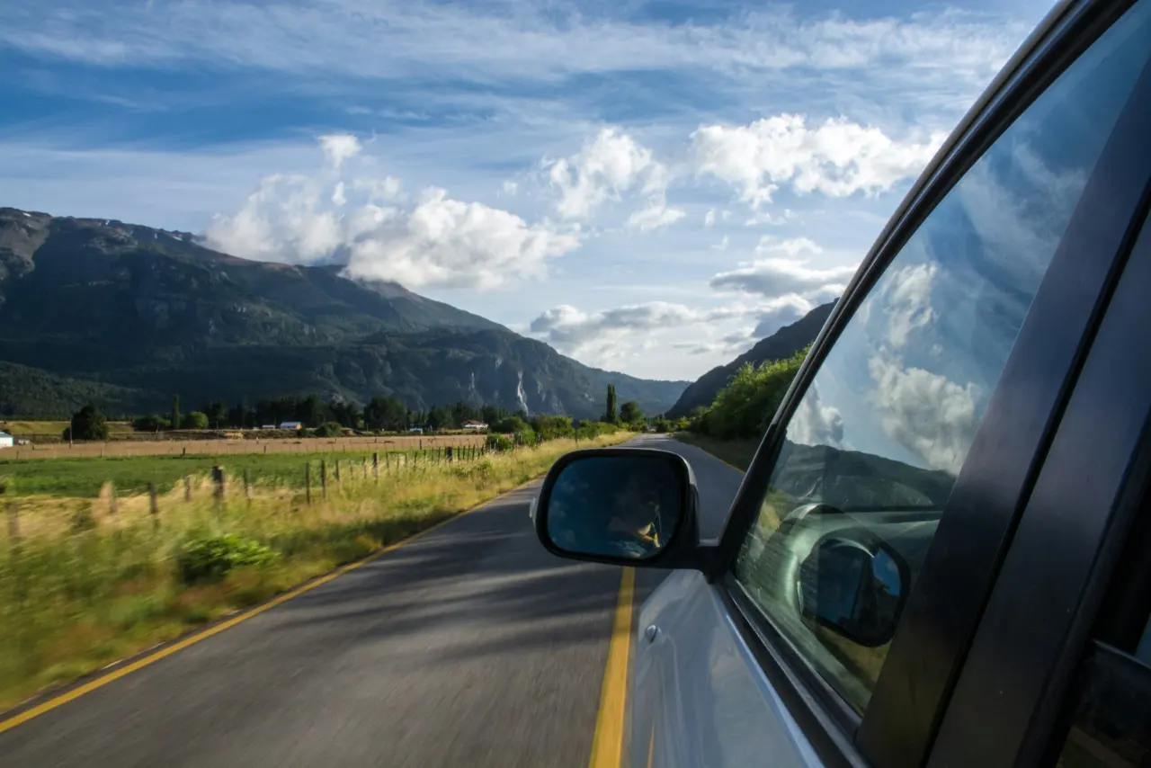 Sürücü koltuğundan görülen dağlar arasındaki asfalt yol